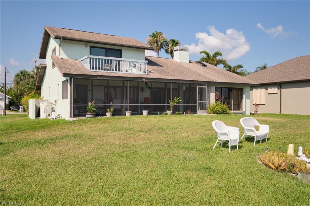 Back of house featuring a yard, a sunroom, and a balcony