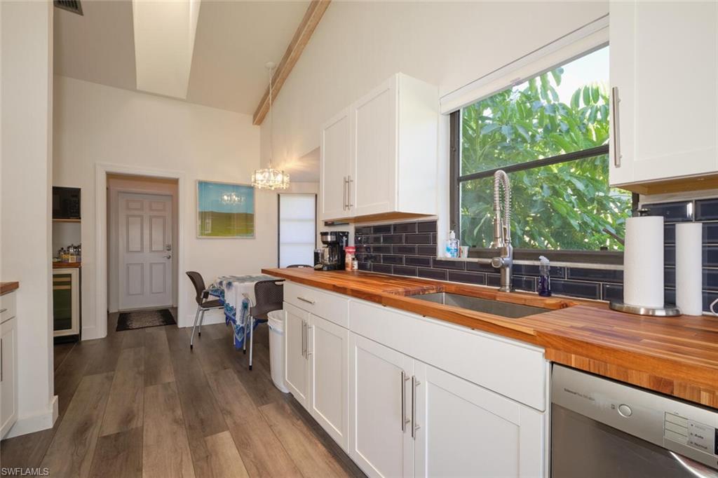 Kitchen featuring butcher block countertops, tasteful backsplash, hardwood / wood-style flooring, and dishwasher