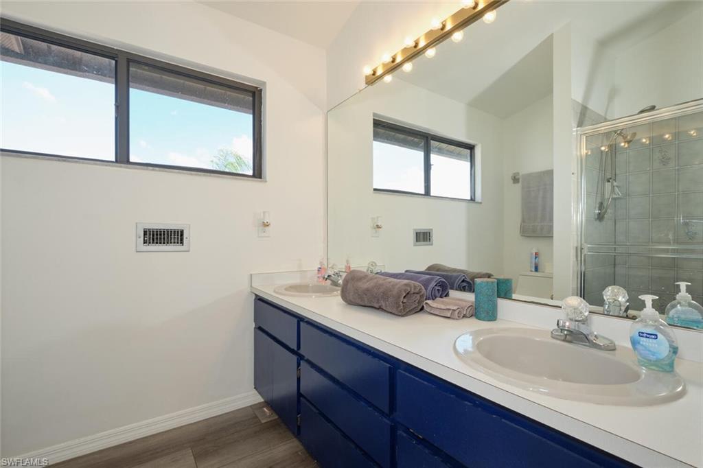 Bathroom featuring dual bowl vanity, plenty of natural light, and walk in shower