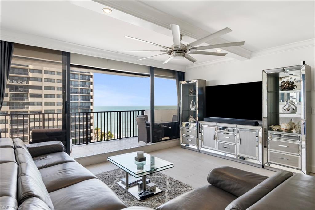 Living room with crown molding, ceiling fan, a wall of windows, and a water view