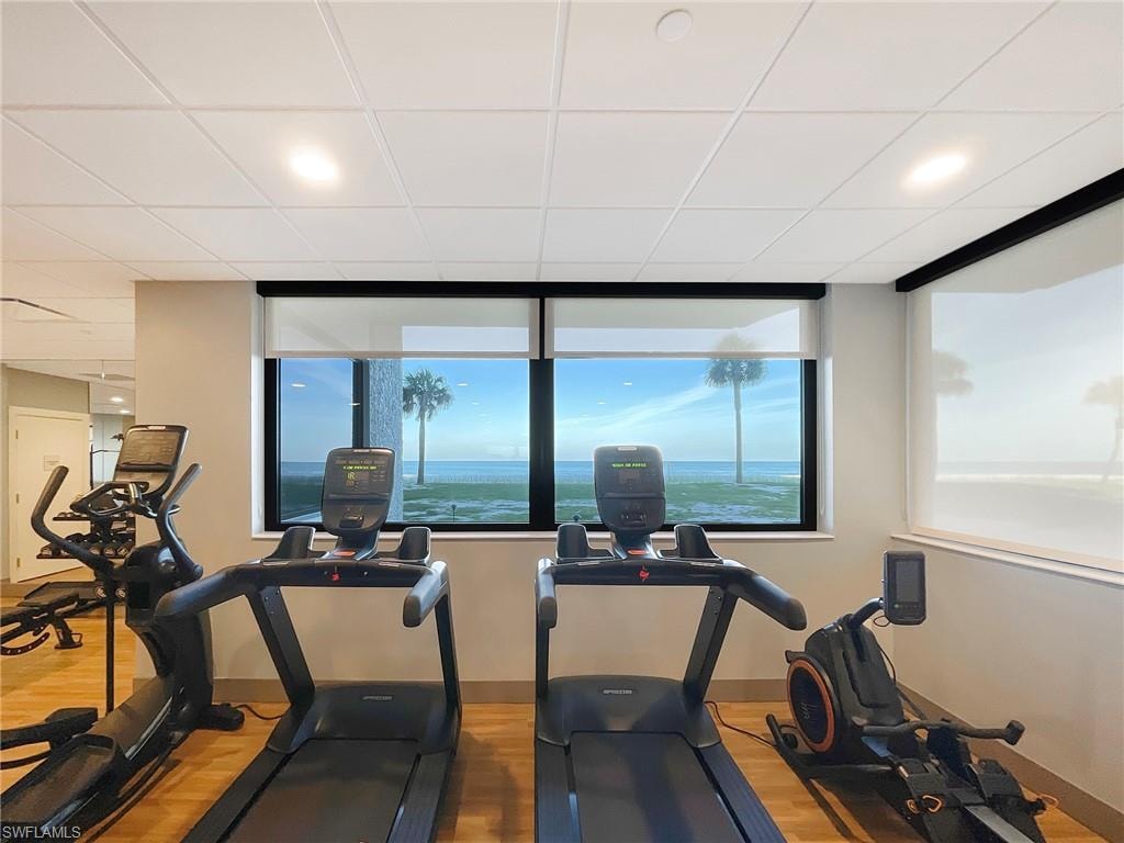 Workout area with light wood-style floors, a paneled ceiling, and recessed lighting