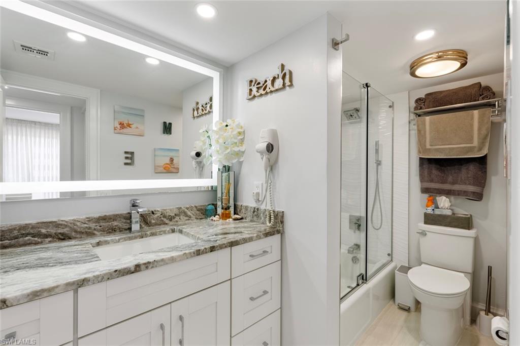Full bathroom featuring tile flooring, enclosed tub / shower combo, vanity, and toilet