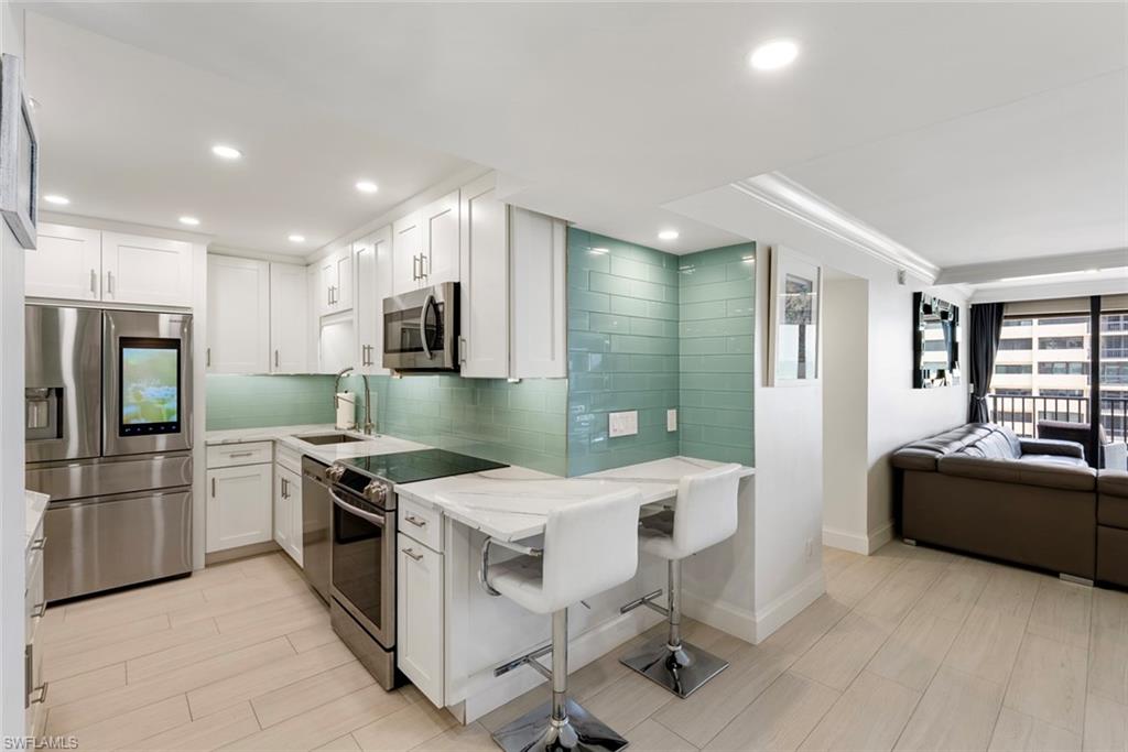 Kitchen with appliances with stainless steel finishes, white cabinetry, and a kitchen breakfast bar