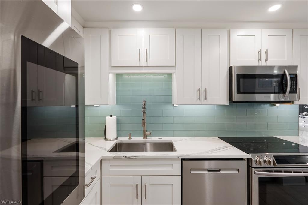 Kitchen featuring sink, white cabinets, tasteful backsplash, and appliances with stainless steel finishes