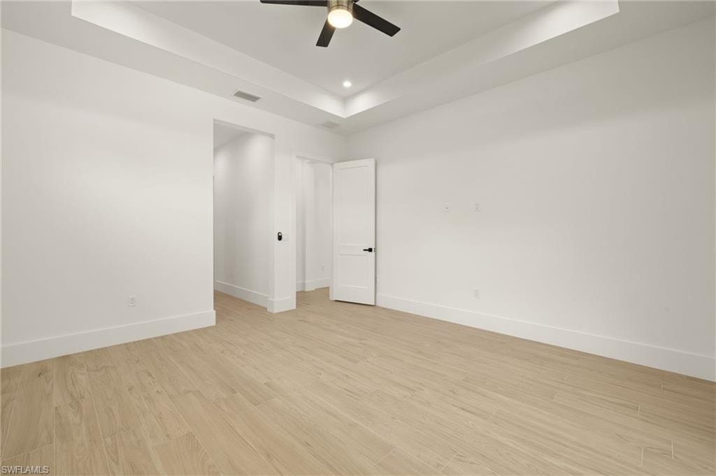 Unfurnished room with a raised ceiling, light wood-style floors, baseboards, and visible vents