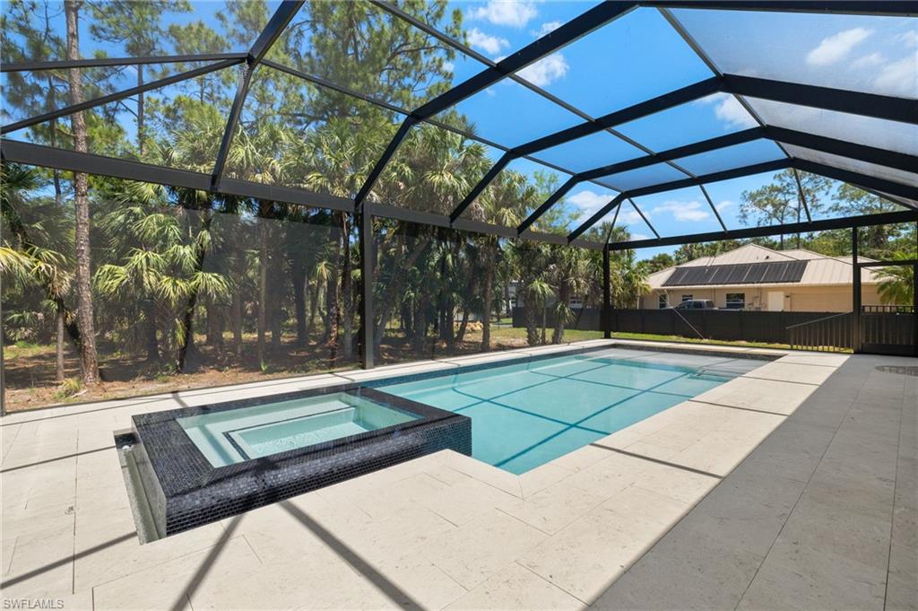 View of pool with a patio, a pool with connected hot tub, and glass enclosure