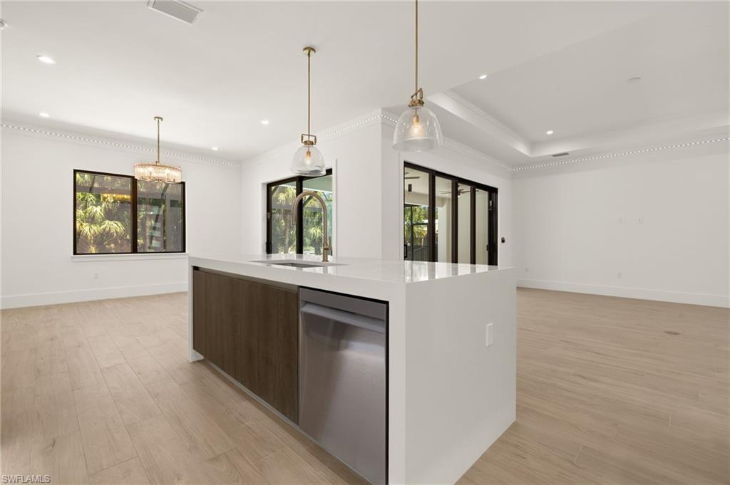 Kitchen with light countertops, light wood-style floors, modern cabinets, stainless steel dishwasher, and a sink
