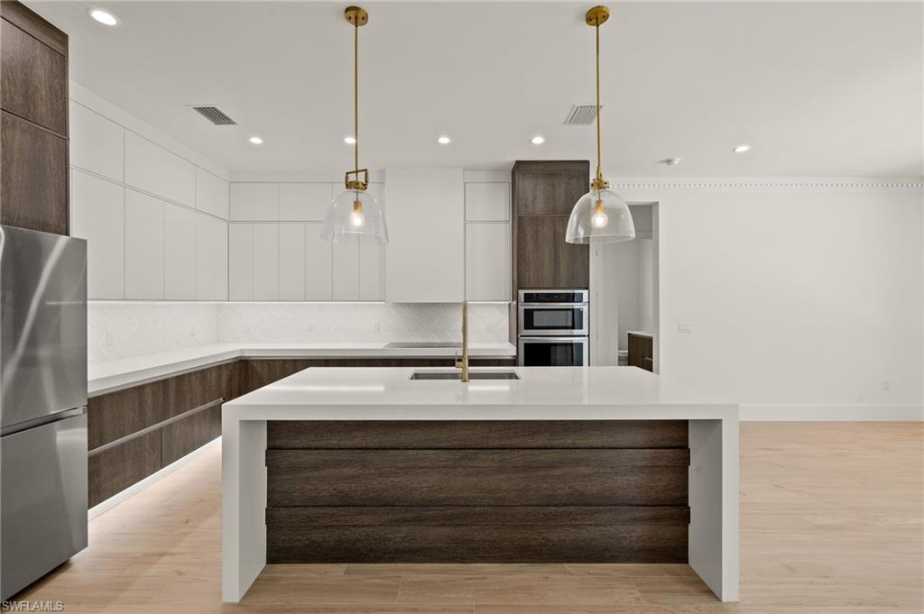 Kitchen with stainless steel appliances, light countertops, modern cabinets, and backsplash