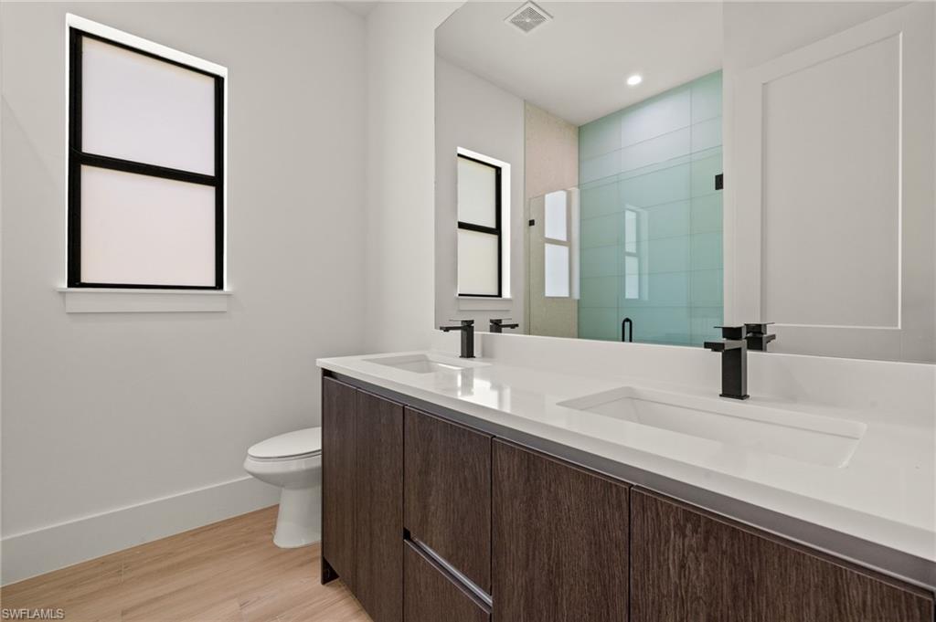 Full bathroom with a shower stall, visible vents, a sink, and toilet