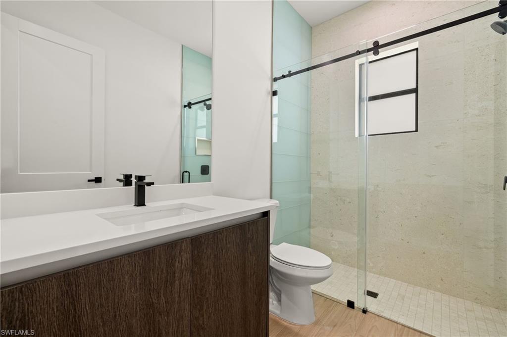 Full bathroom featuring a shower stall, vanity, toilet, and wood finished floors