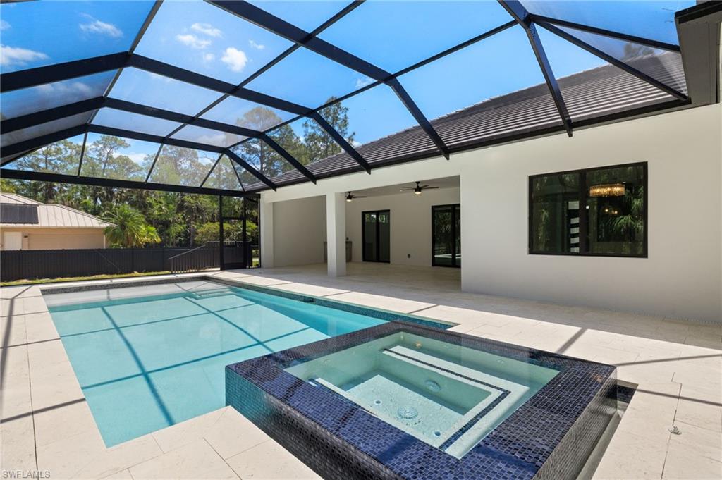 View of pool featuring a patio, a pool with connected hot tub, glass enclosure, and ceiling fan