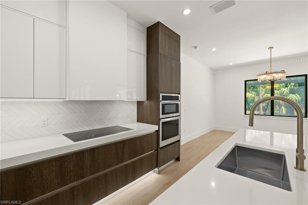 Kitchen featuring light countertops, white cabinetry, visible vents, modern cabinets, and a sink