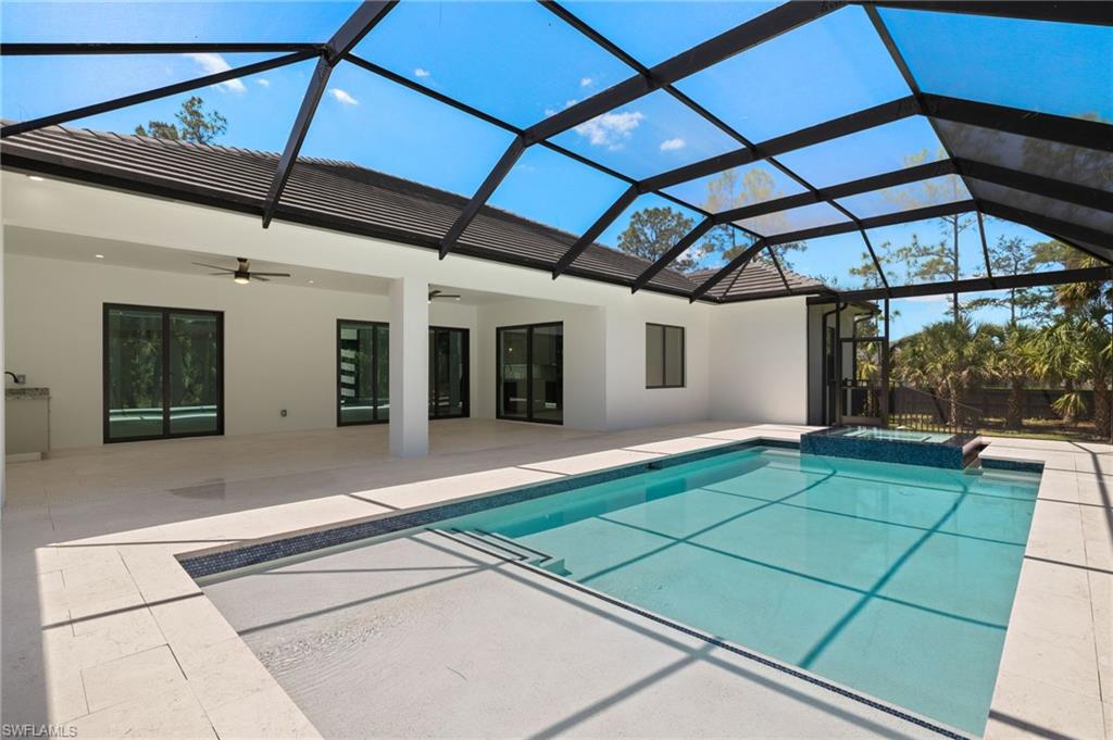 View of pool with a patio area, a pool with connected hot tub, a ceiling fan, and glass enclosure