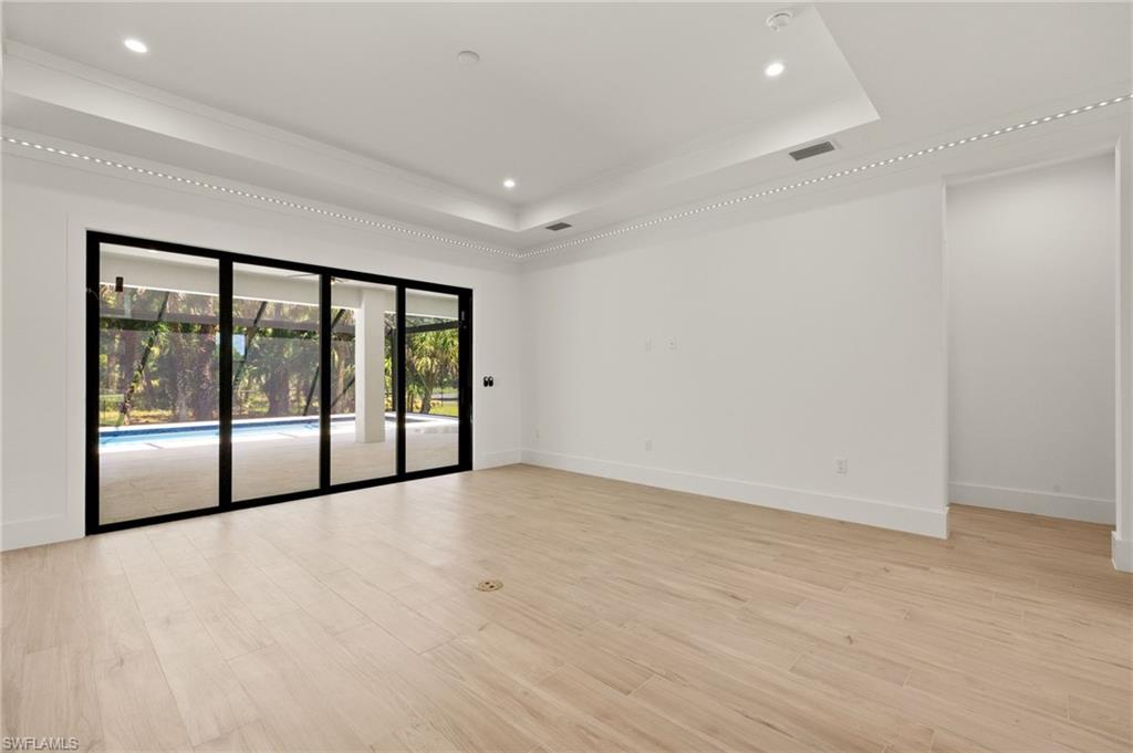 Unfurnished room with light wood-style floors, visible vents, baseboards, and a raised ceiling