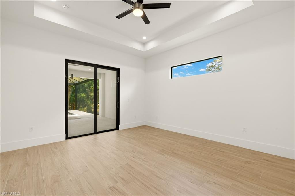 Unfurnished room featuring light wood-style floors, baseboards, and a raised ceiling