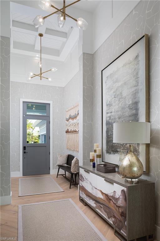 Foyer with beam ceiling, a notable chandelier, coffered ceiling, and wood-type flooring