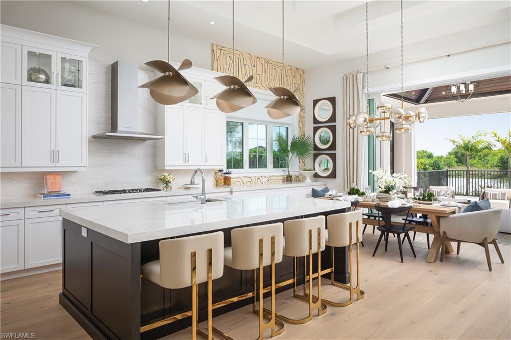 Kitchen with wall chimney range hood, sink, backsplash, and light hardwood / wood-style flooring