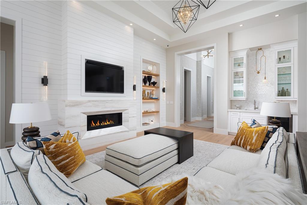 Living room with a fireplace, light hardwood / wood-style flooring, built in shelves, a chandelier, and sink