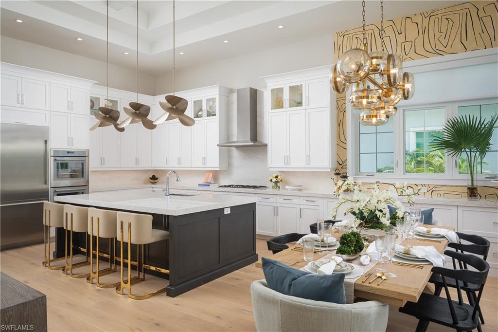 Kitchen featuring an island with sink, wall chimney exhaust hood, light hardwood / wood-style flooring, and white cabinetry