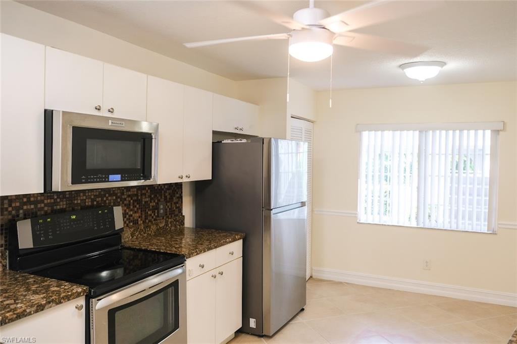 Kitchen with ceiling fan, decorative backsplash, stainless steel appliances, and white cabinets