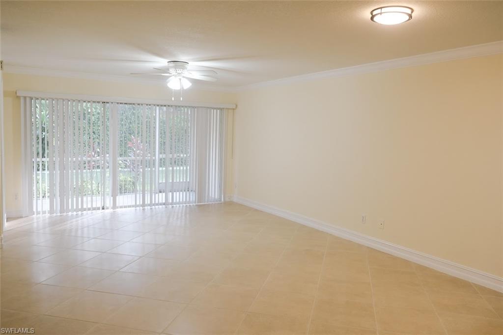 Tiled empty room featuring ceiling fan and ornamental molding