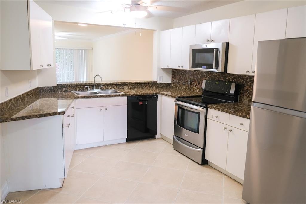Kitchen featuring appliances with stainless steel finishes, white cabinets, ceiling fan, sink, and dark stone counters