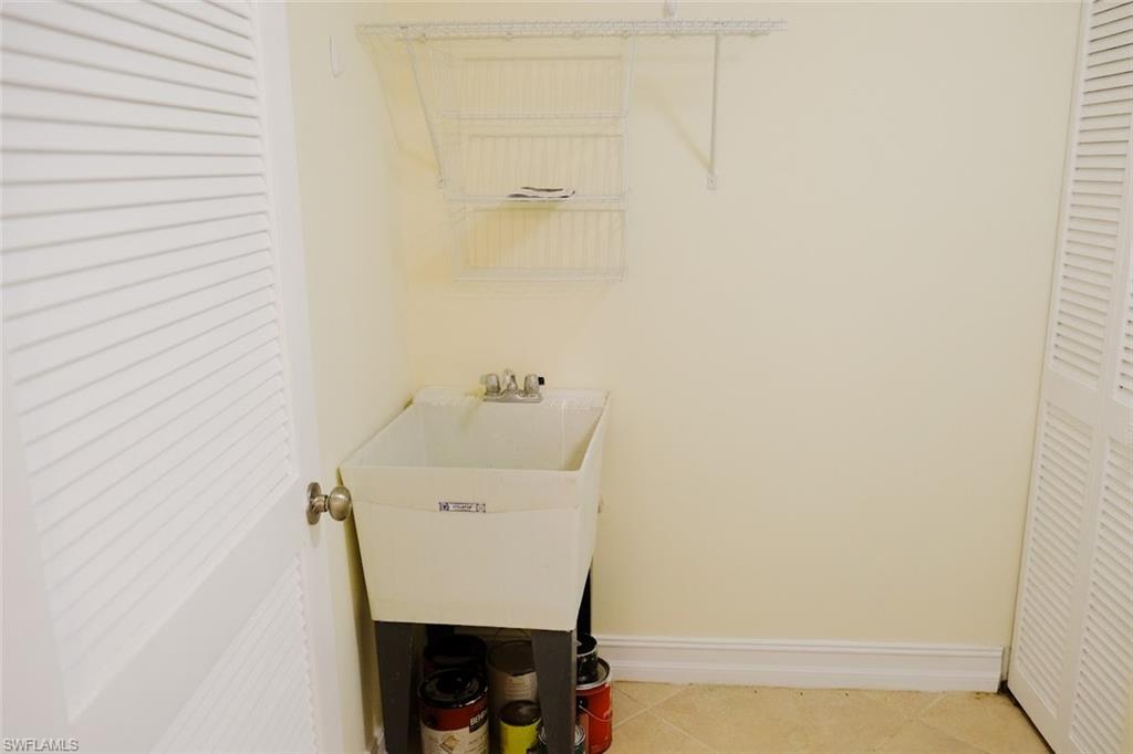 Clothes washing area with sink and light tile patterned floors