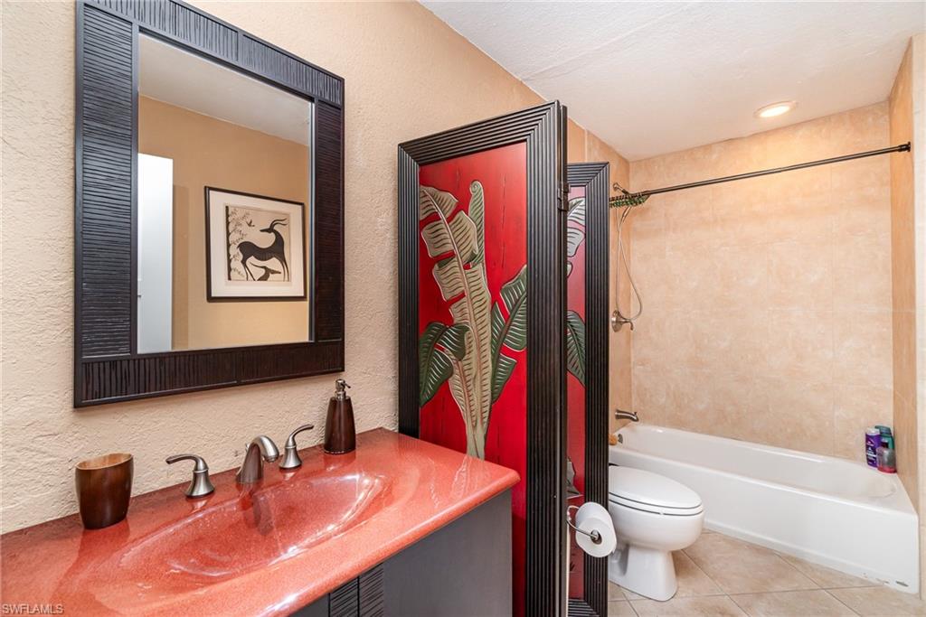 Full bathroom featuring tile floors, vanity, toilet, and tiled shower / bath combo