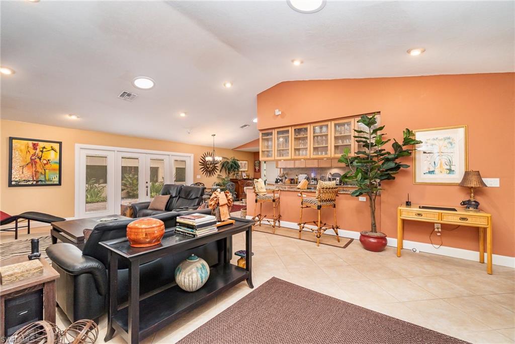 Living room featuring light tile floors, french doors, and vaulted ceiling