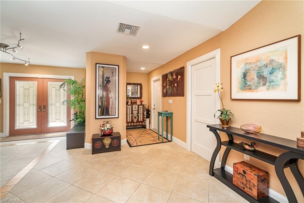 Foyer featuring light tile floors, track lighting, and french doors