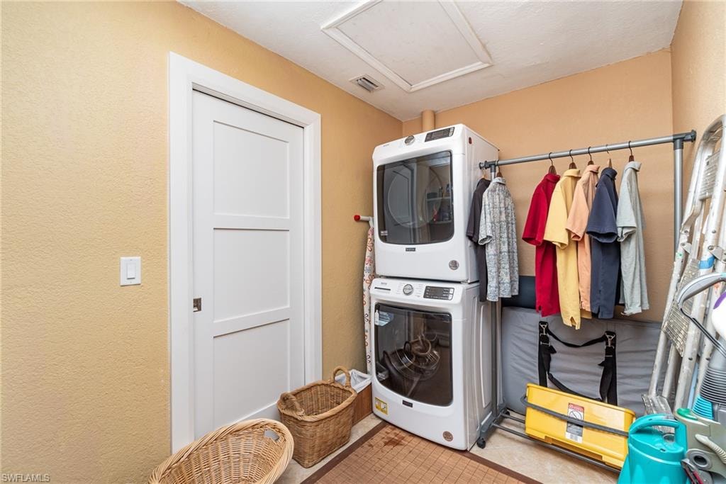 Clothes washing area with stacked washing maching and dryer and tile floors