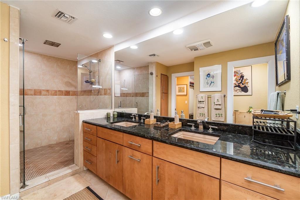 Bathroom featuring tile flooring, walk in shower, and dual vanity