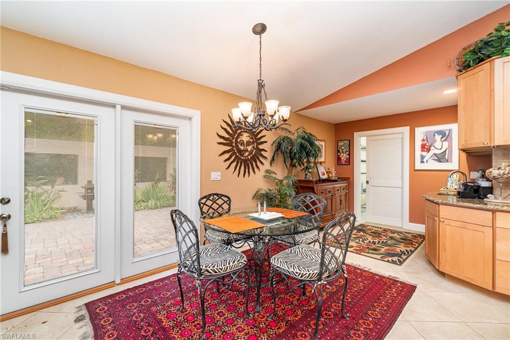 Tiled dining area featuring lofted ceiling and a chandelier