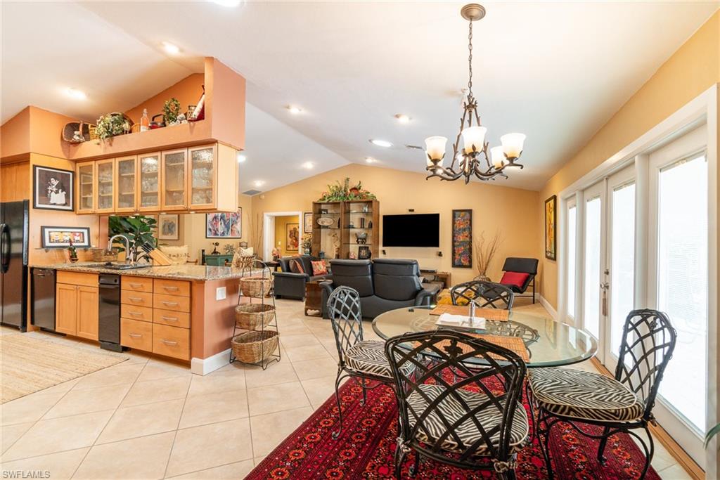 Tiled dining space with sink, lofted ceiling, and a chandelier