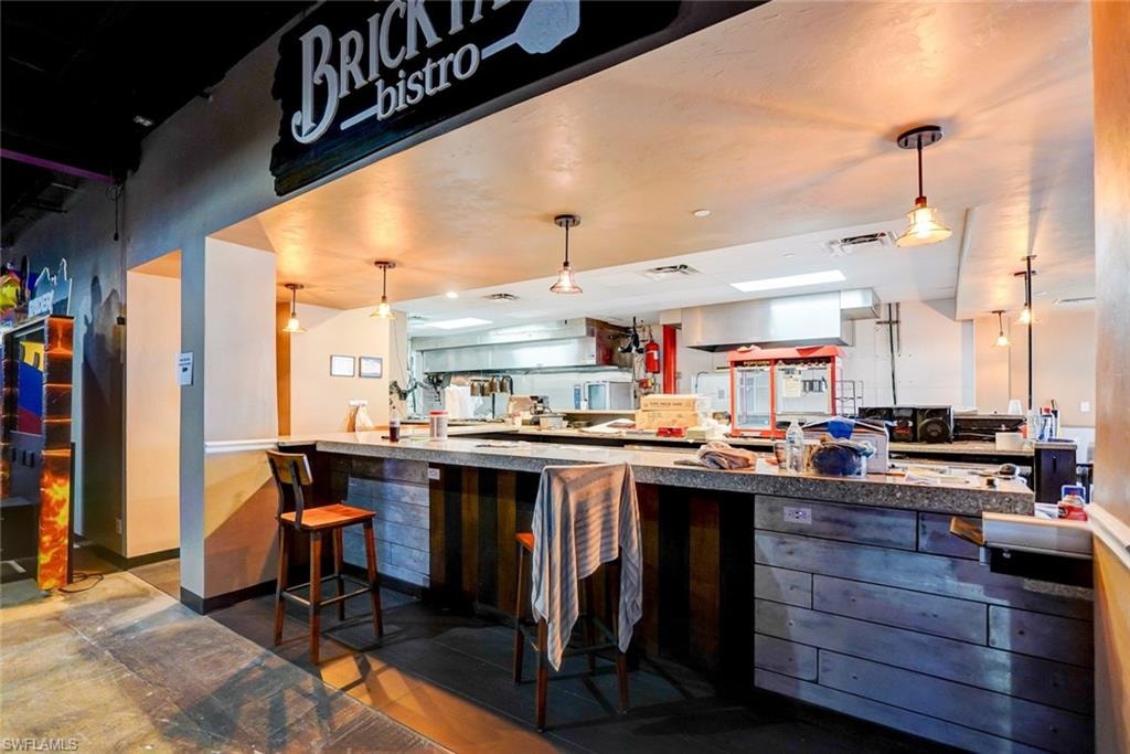 Kitchen featuring dark tile flooring, kitchen peninsula, a kitchen bar, and pendant lighting