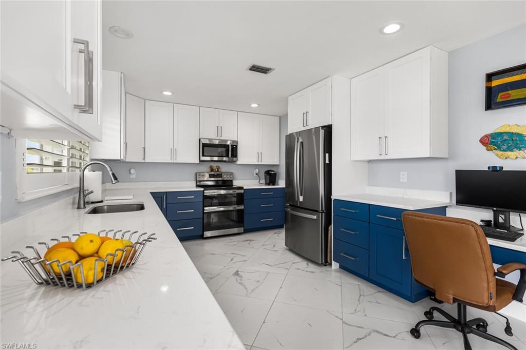 Kitchen featuring quartz counter tops, GE stove with convection oven and air fryer, GE refrigerator / freezer. Past the refrigerator and oven is access to Laundry Room.