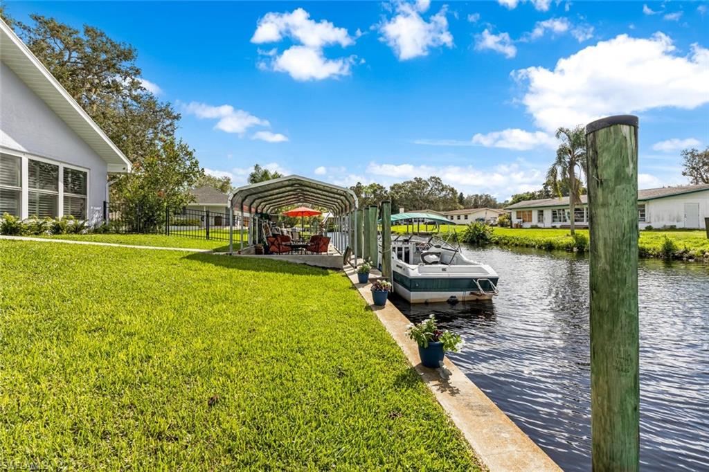 View of dock and seawall along with covered dock landing area.  Also fence is in view.  Great for letting your pets have room to play.