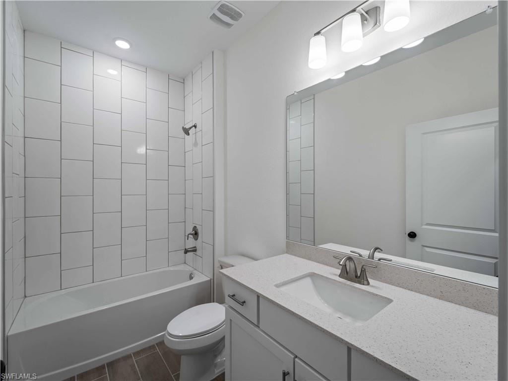 Full bathroom featuring toilet, tub / shower combination, vanity, and wood tiled floors
