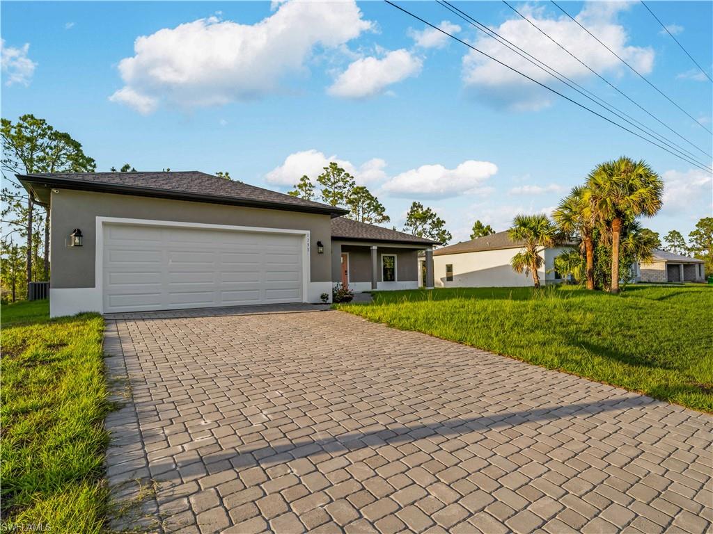Ranch-style house with stucco siding, decorative driveway, a front yard, and a garage