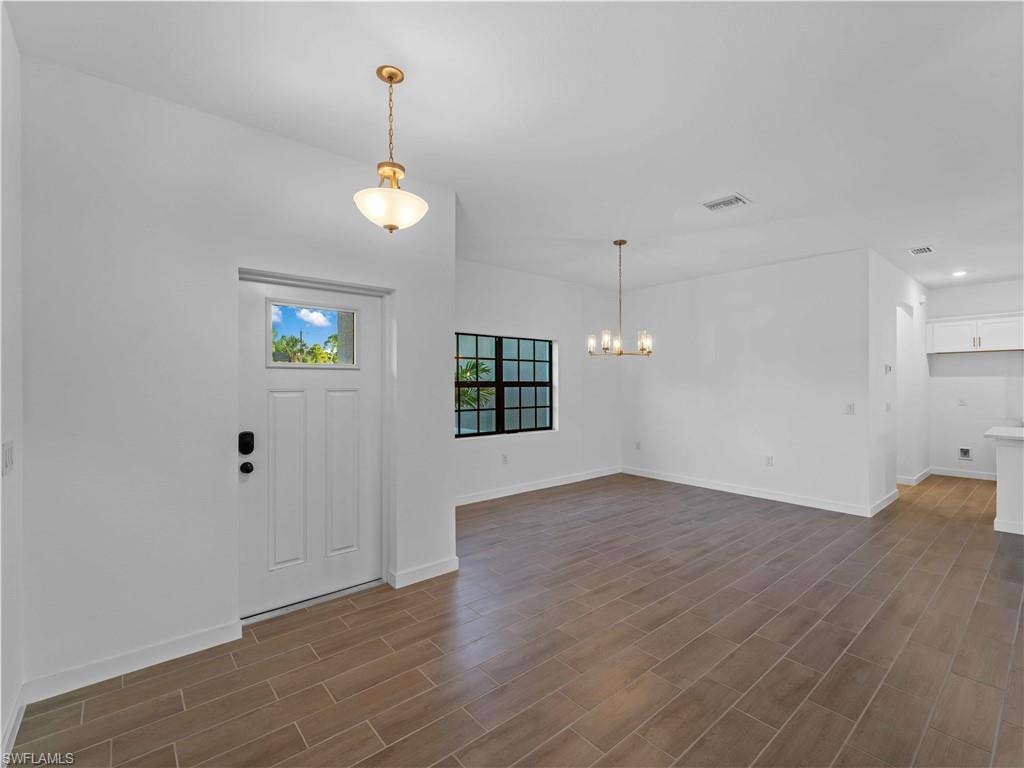 Foyer featuring a chandelier, dark wood-style floors, baseboards, and recessed lighting