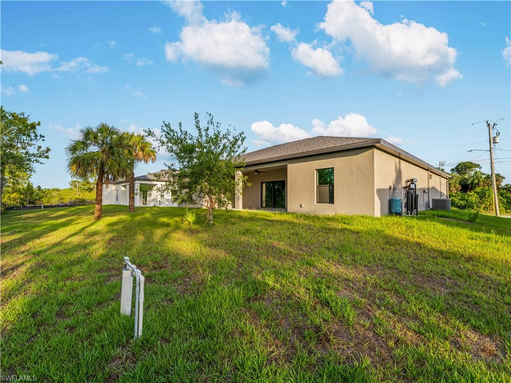 Rear view of house featuring stucco siding, central air condition unit, a lawn, and ceiling fan