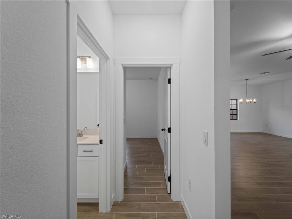 Hall featuring wood tiled floors, a chandelier, baseboards, and a sink