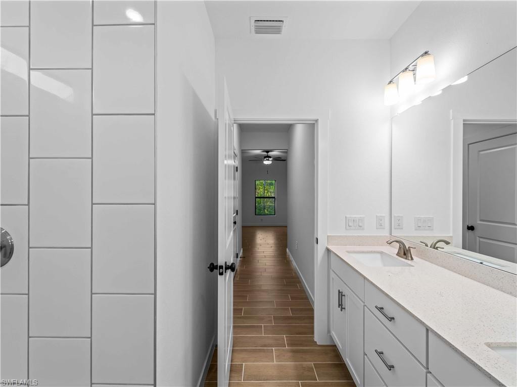 Full bathroom with wood tiled floors, baseboards, a ceiling fan, and double vanity