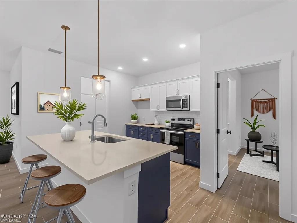Virtually staged Kitchen with light countertops, stainless steel appliances, white cabinetry, a breakfast bar, and wood finish floors