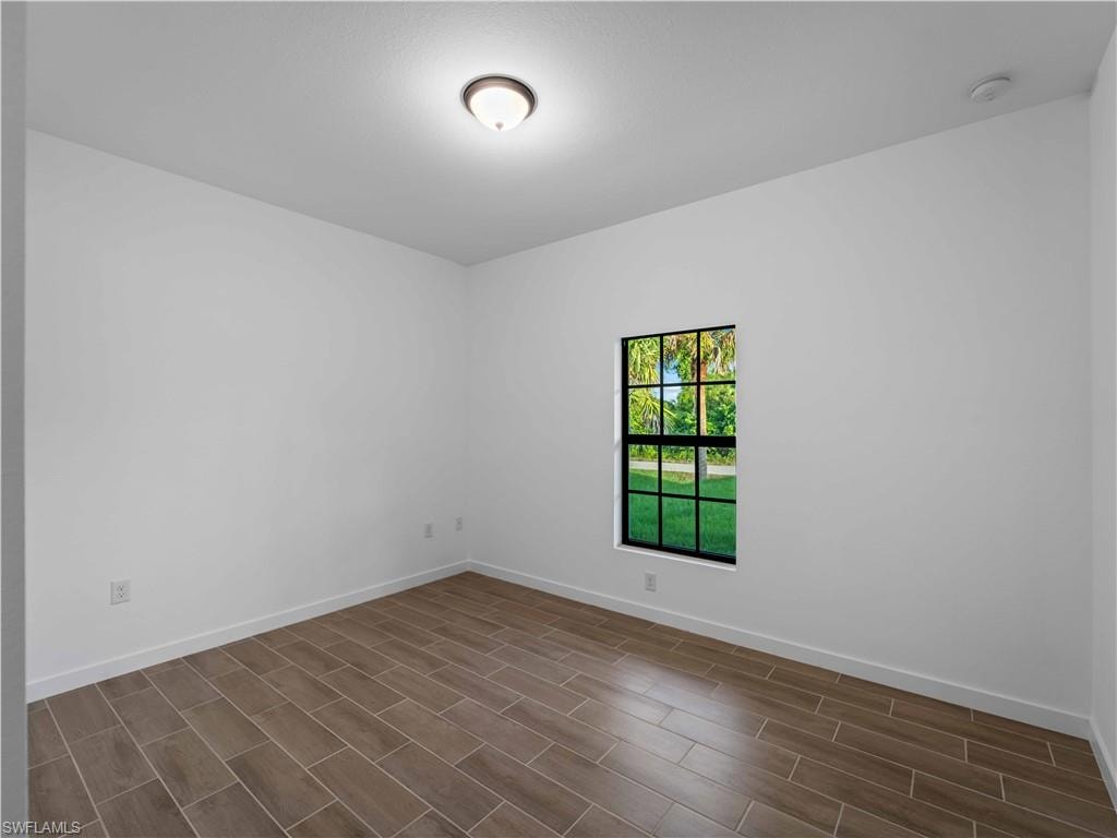 Empty room featuring baseboards and dark wood-type flooring