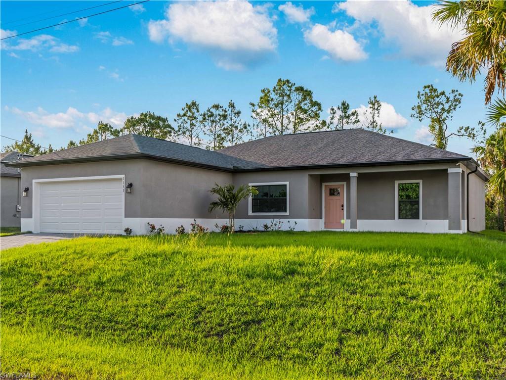 Ranch-style home with an attached garage, stucco siding, a front yard, and driveway