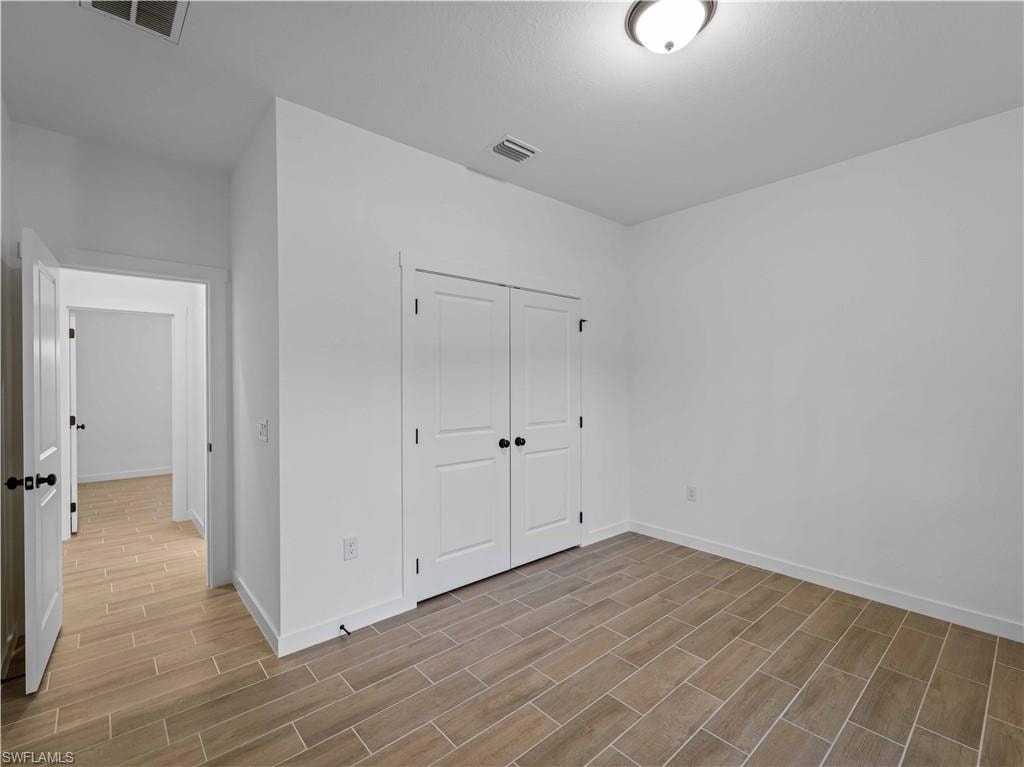 Unfurnished bedroom with wood finish floors, baseboards, and a closet