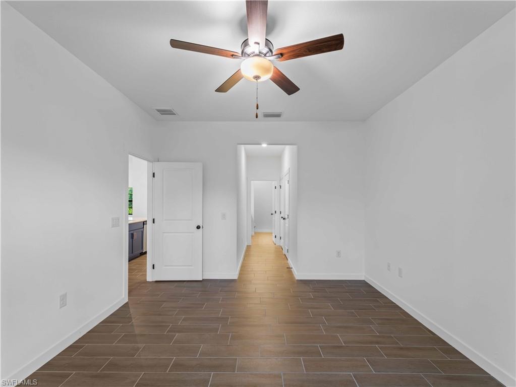 Unfurnished bedroom with baseboards, dark wood-type flooring, and ceiling fan