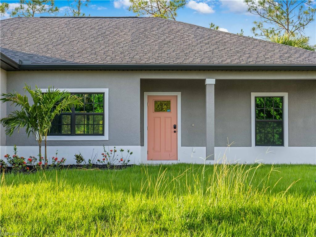 View of front of house featuring a shingled roof and stucco siding