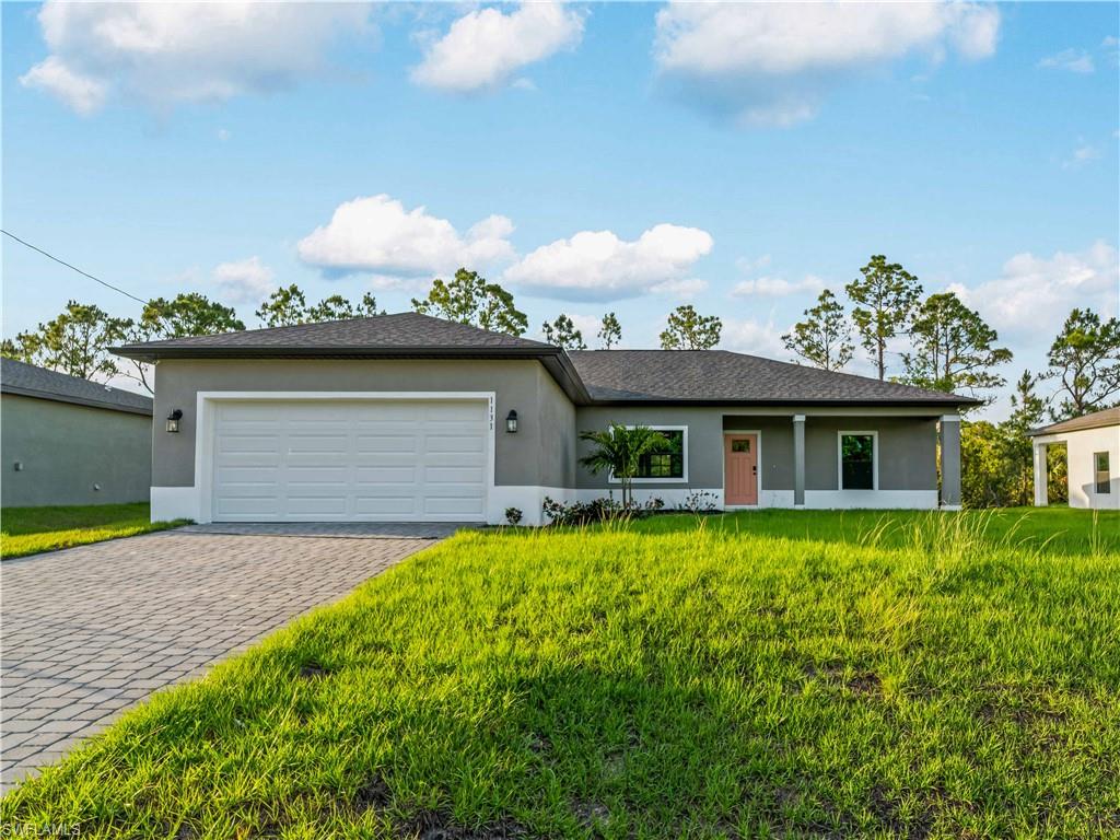 View of front of home featuring stucco siding, a garage, decorative driveway, and a front yard